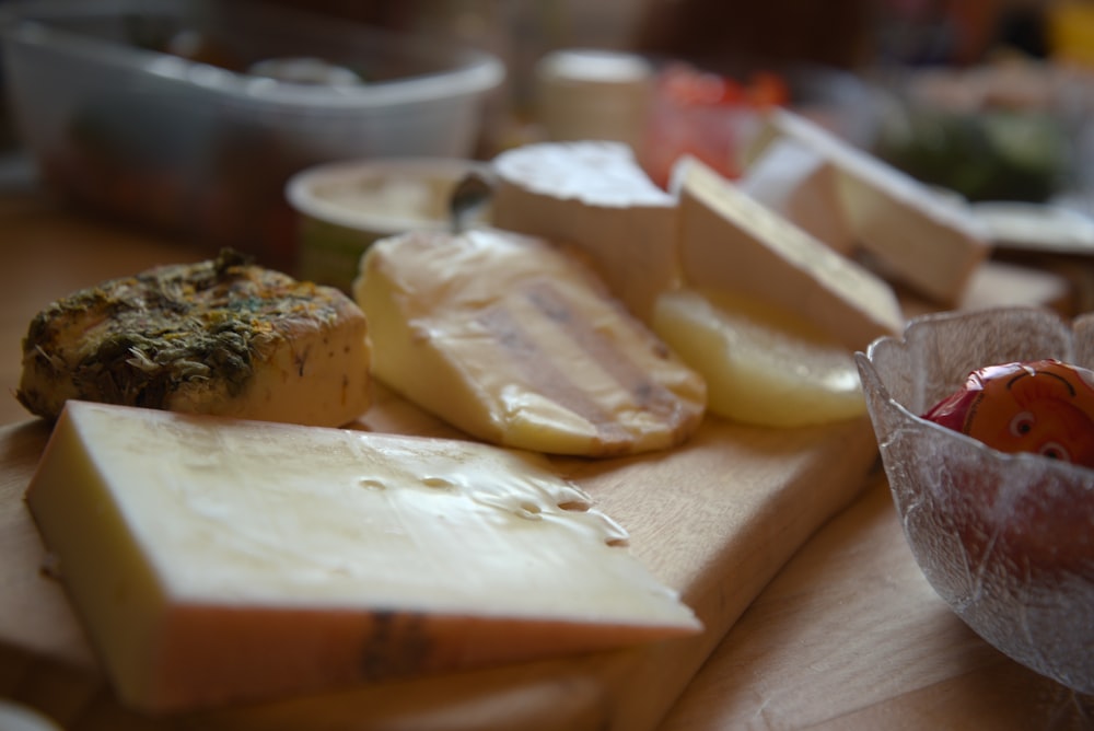 a variety of cheeses are on a cutting board