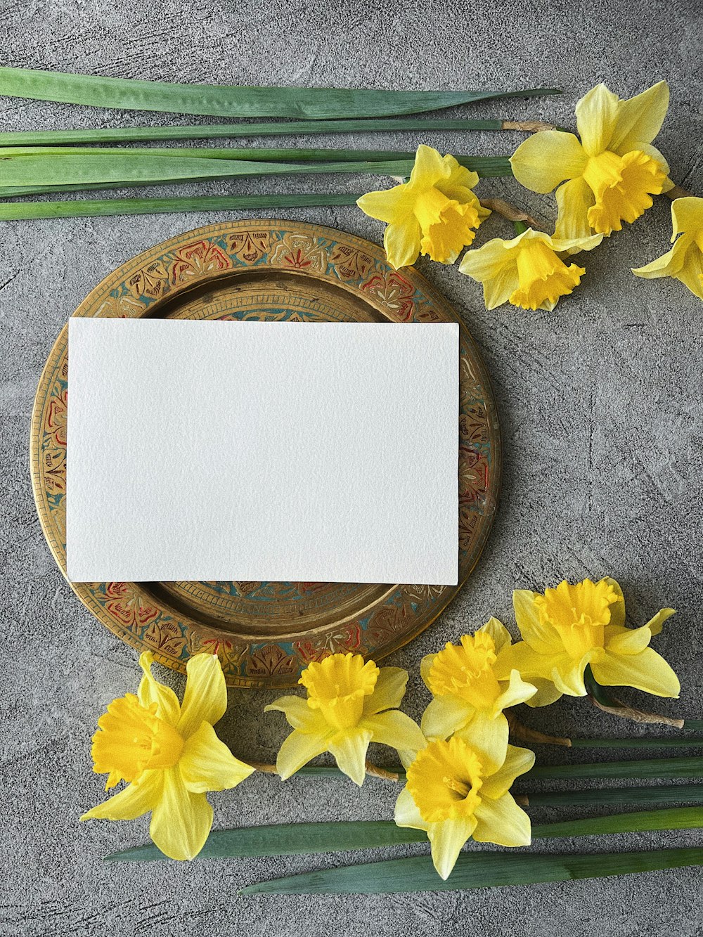 a plate with a blank card on it next to yellow flowers