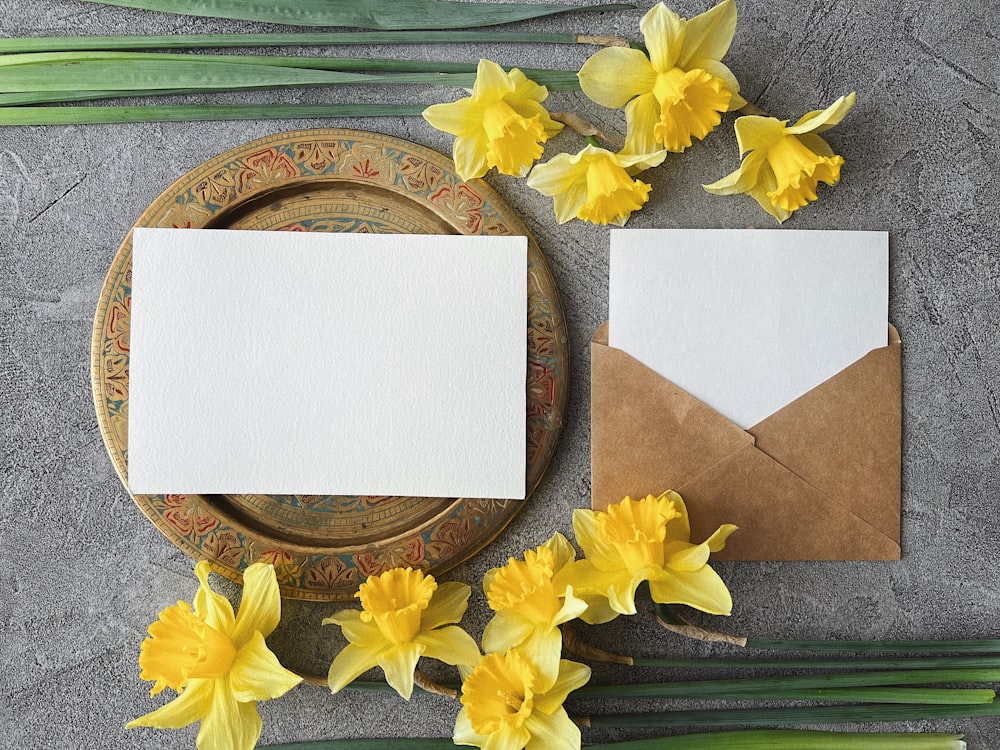 a table topped with yellow flowers and an envelope