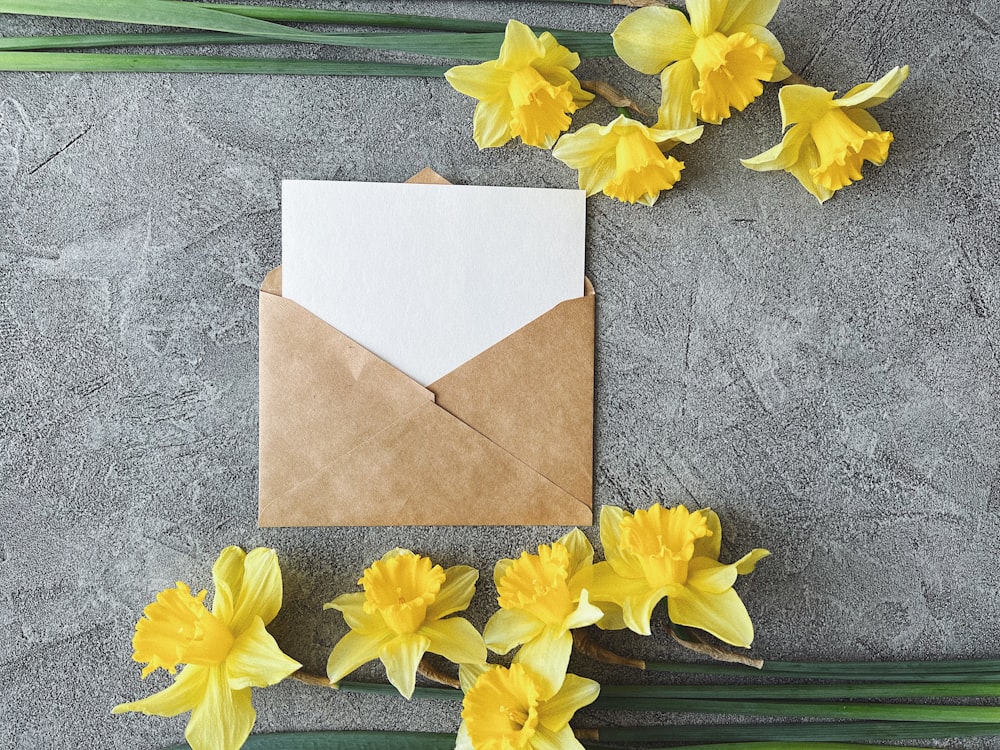 a brown envelope with a white paper and some yellow flowers