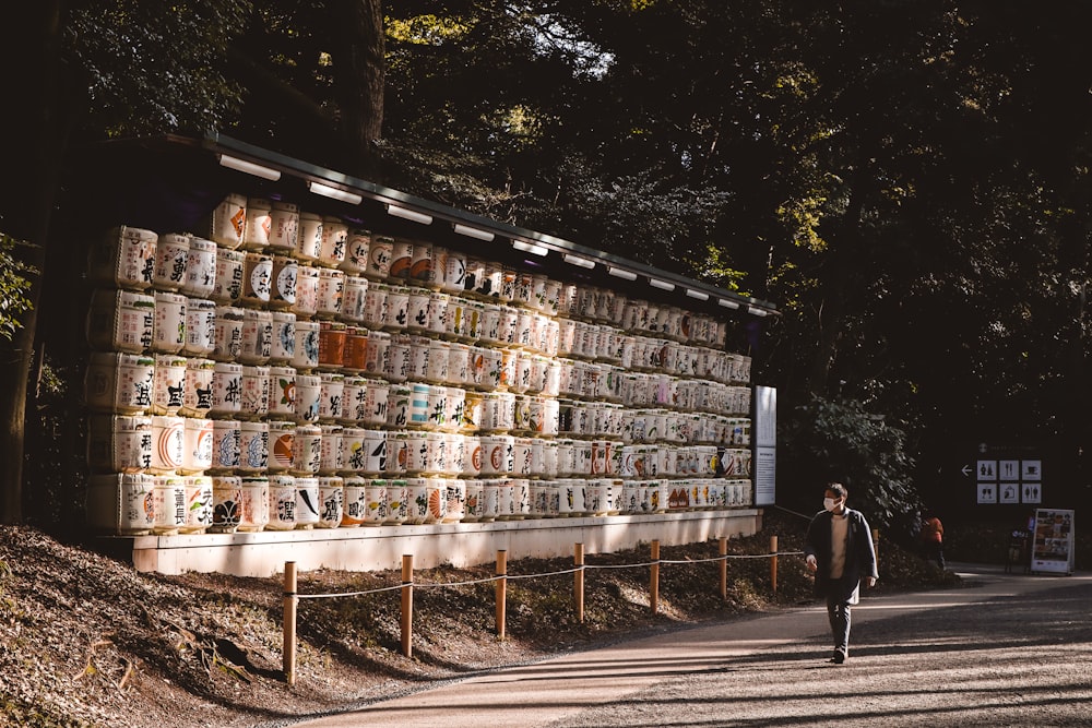 a man walking down a street past a wall covered in pictures