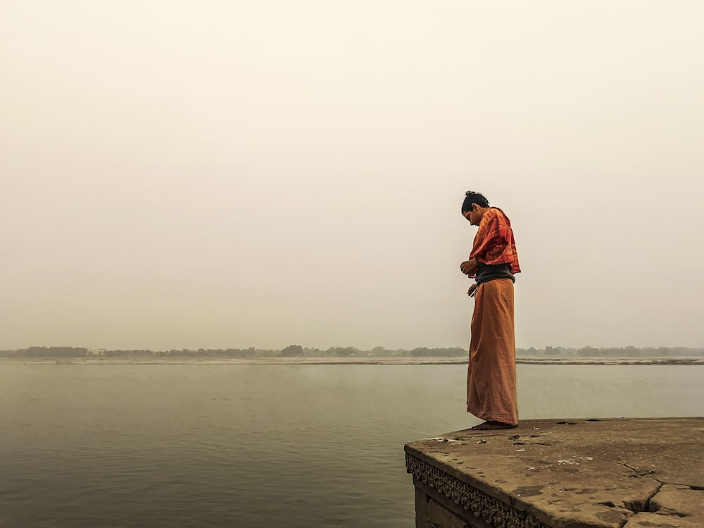 a man standing on the edge of a pier next to a body of water