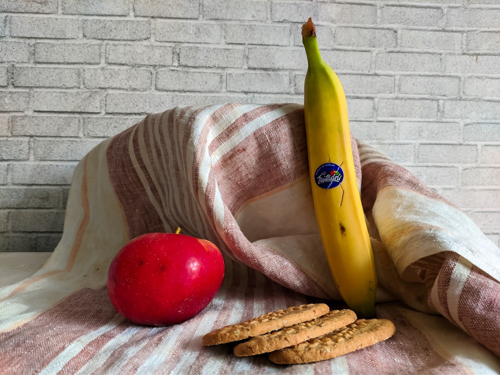 a banana, apple, and cookies on a blanket
