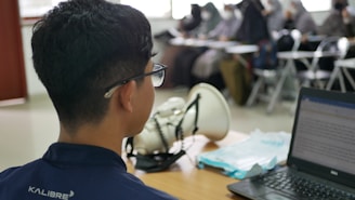 a man sitting at a desk using a laptop computer