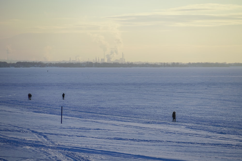 a couple of people walking across a snow covered field