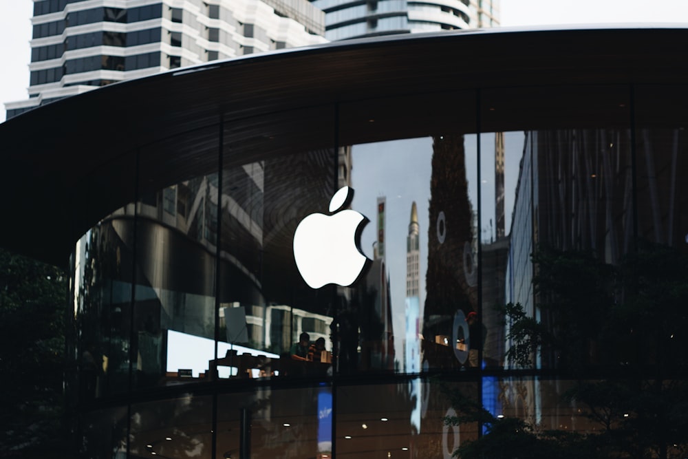 the apple logo is reflected in the glass of a building
