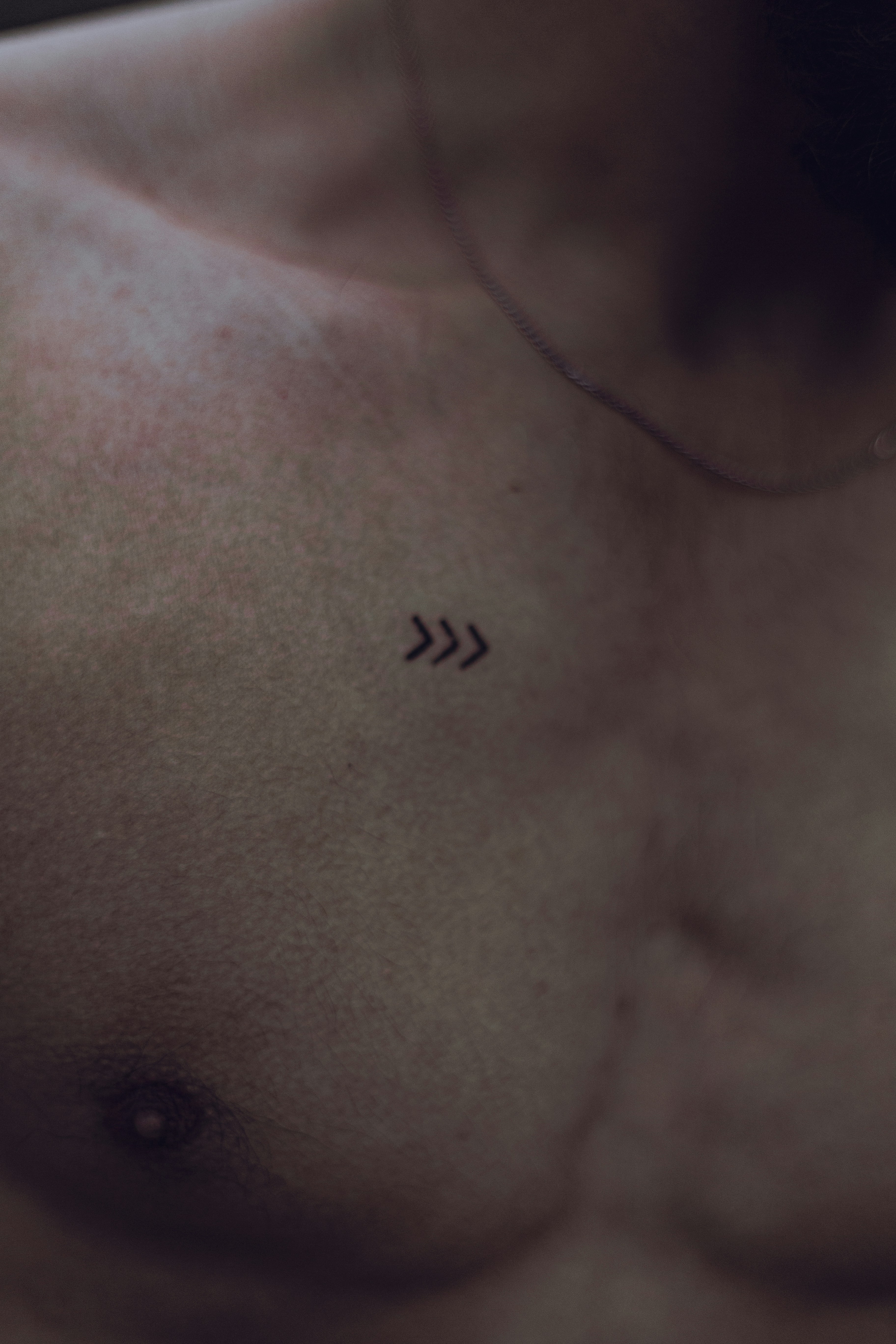 a close up of a man's chest with an arrow tattoo