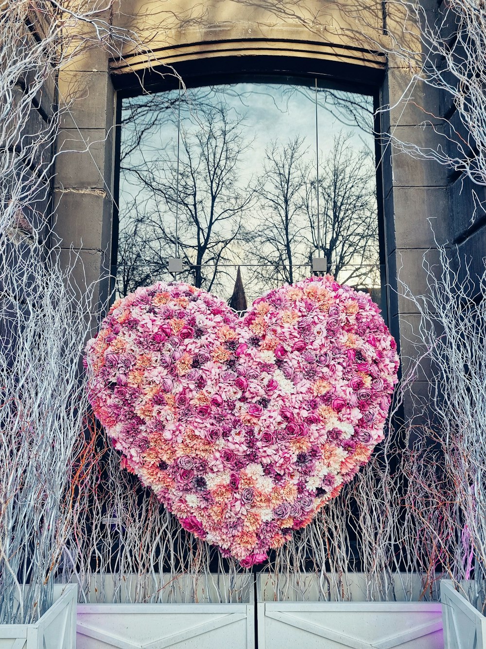 a large heart made of flowers is in front of a building