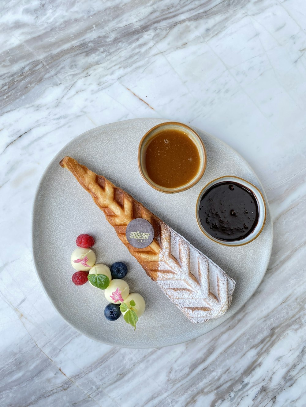 a white plate topped with a pastry next to a cup of coffee