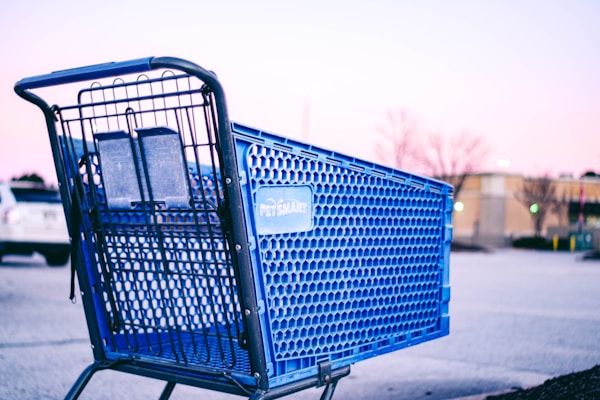 a blue shopping cart sitting on the side of a road