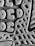 A close-up view of a textured surface, featuring a pattern of geometric shapes like circles and triangles. The material appears rubbery, with a detailed tread design suggesting it might be the sole of a shoe.