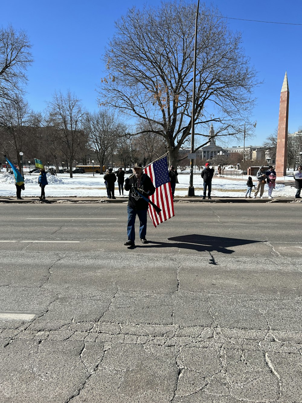 a person holding an american flag in the middle of a street