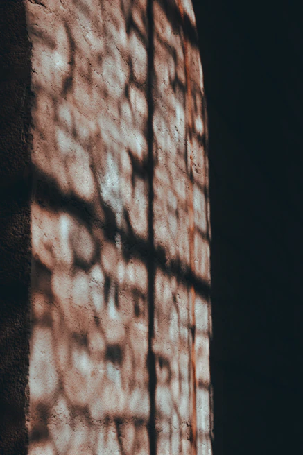 Close-up of a sleek luminara uplight casting gentle shadows on a textured wall