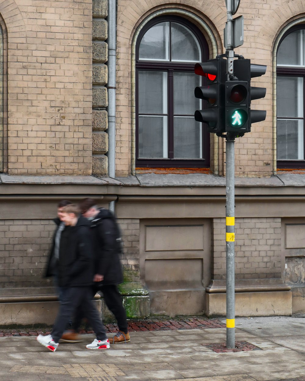 a couple of men walking down a street next to a traffic light