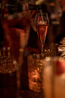 Guests clinking glasses with shimmering cocktails in a modern, dimly lit setting.