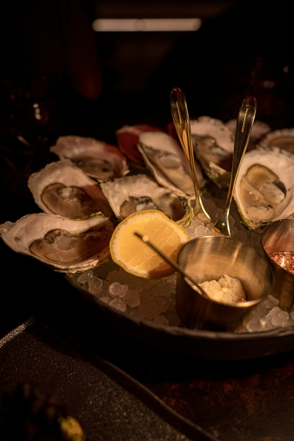 a plate of oysters on ice with lemon wedges