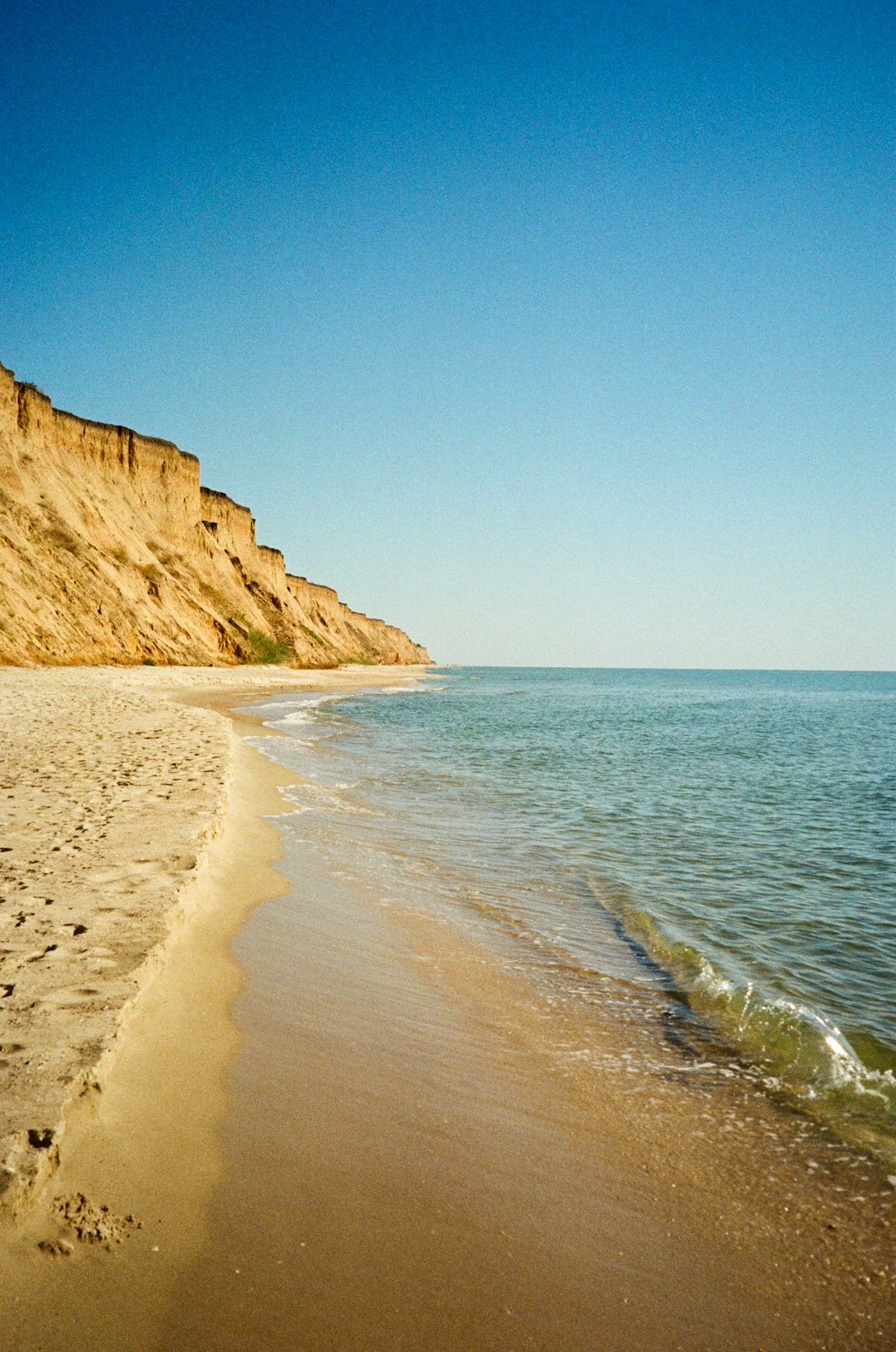 a sandy beach with a cliff in the background