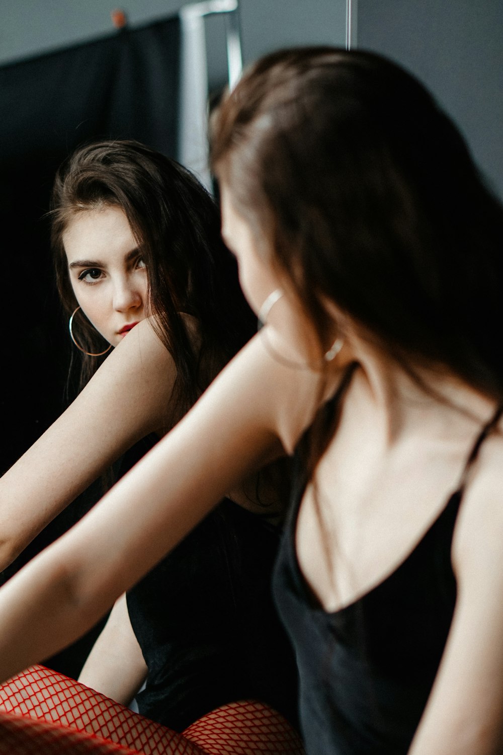 a woman sitting on a bed looking at herself in the mirror