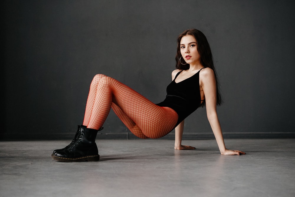 a woman in a black top and red fishnet tights
