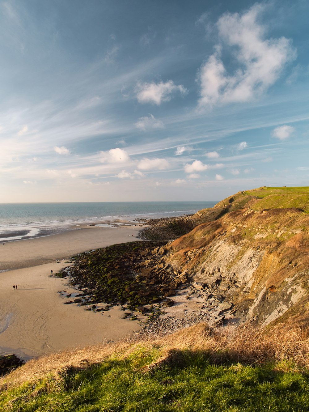 a sandy beach next to the ocean under a blue sky