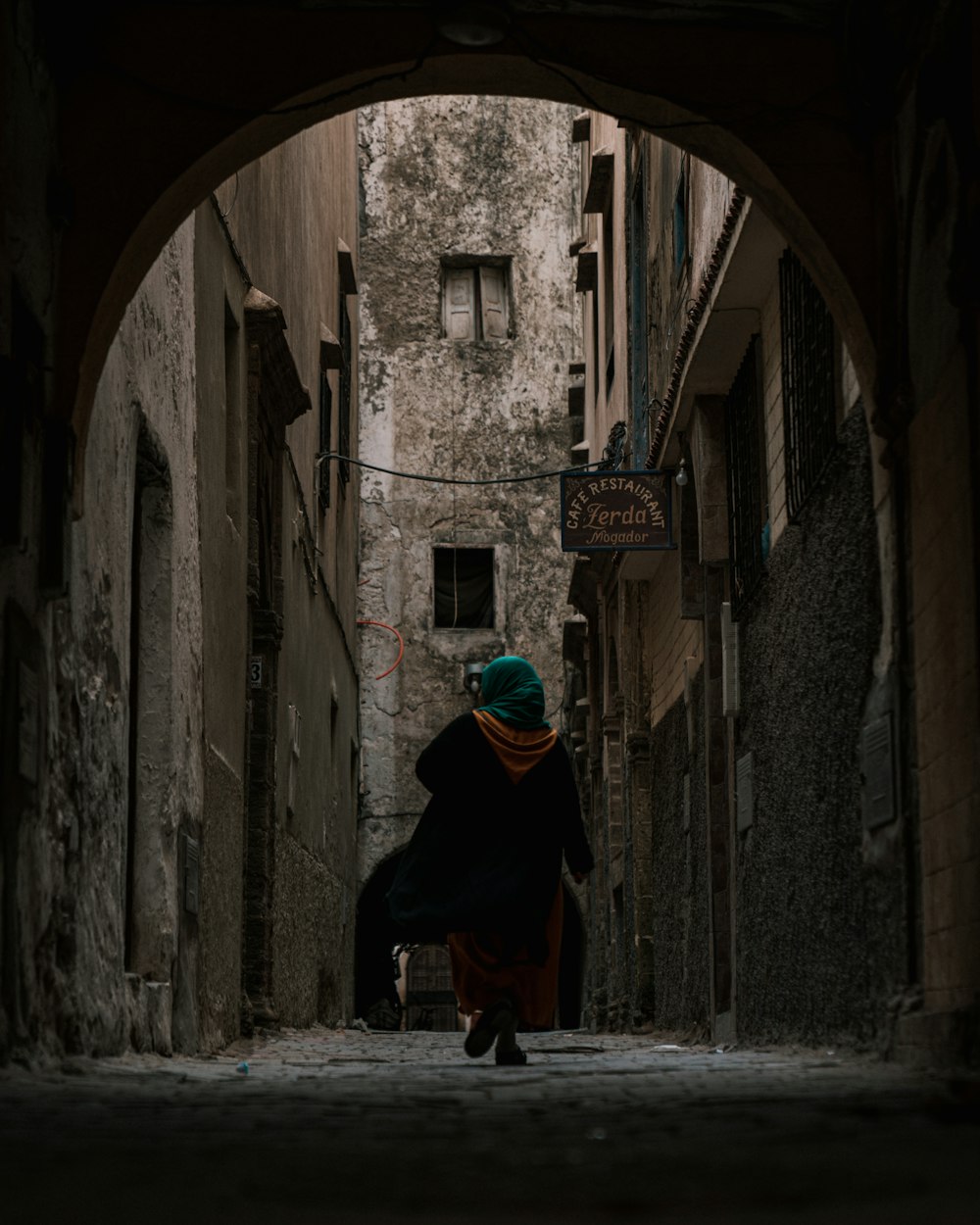 a woman walking down a narrow alley way