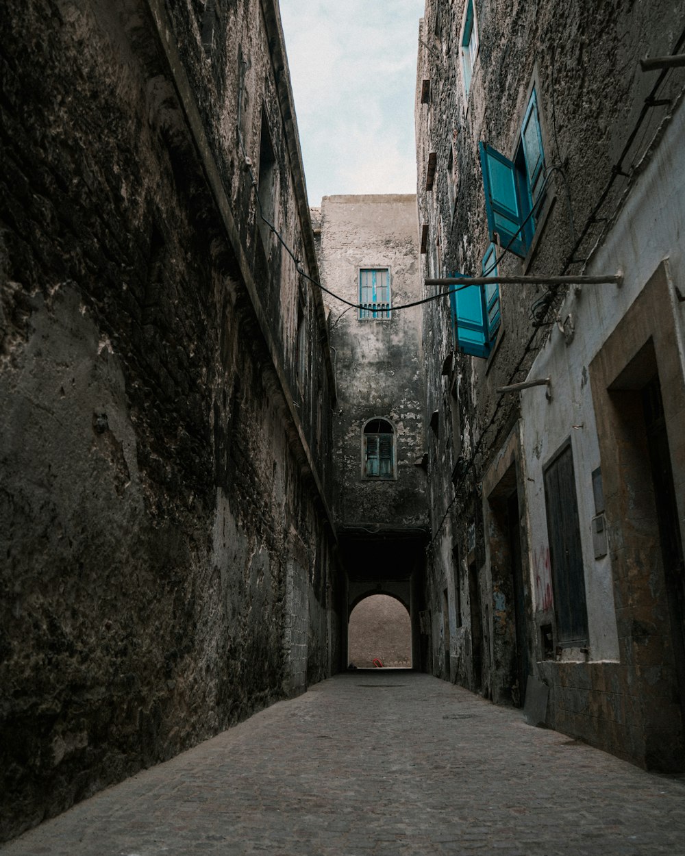 a narrow alley way with blue shutters on the windows