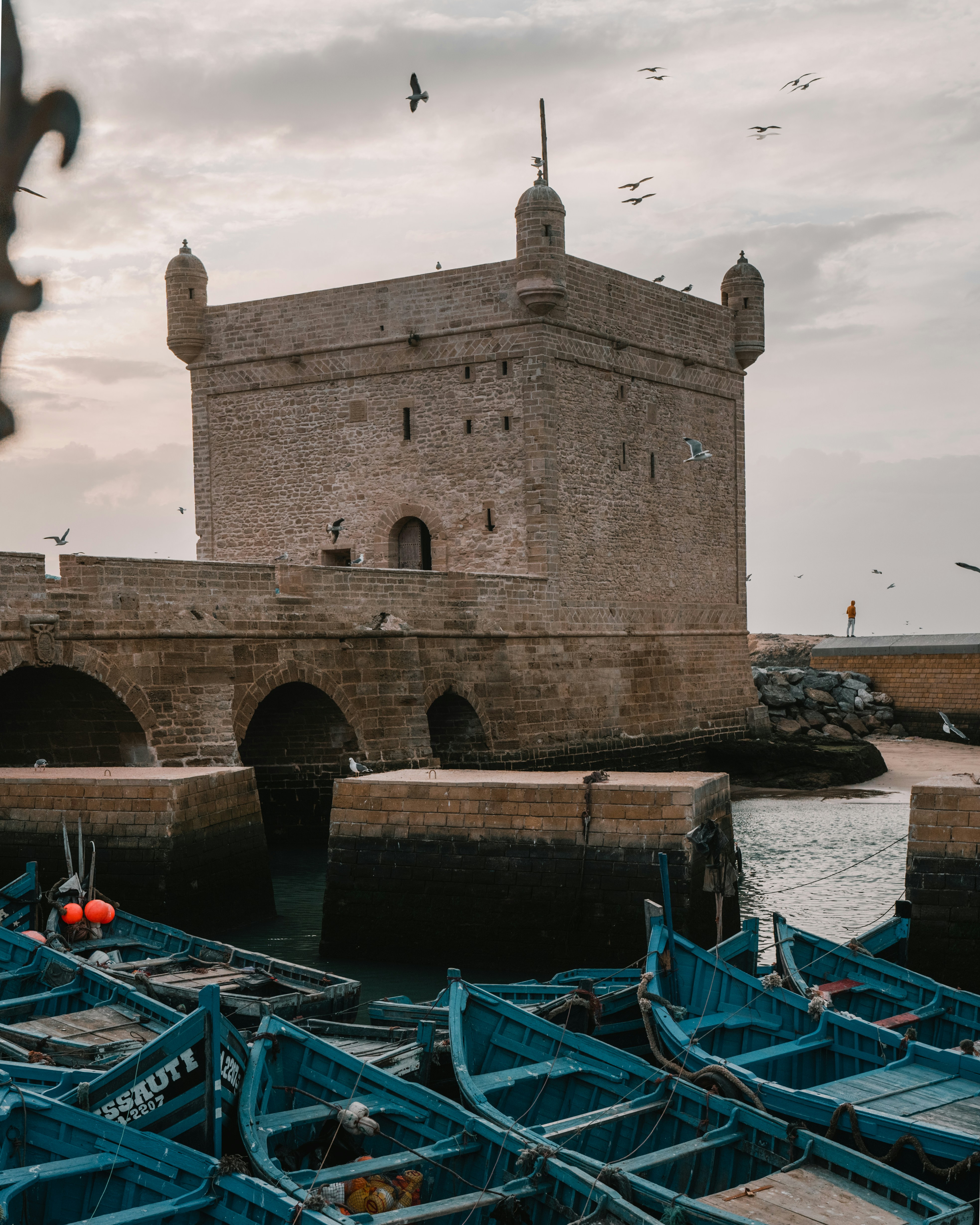 a group of blue boats sitting next to a stone building