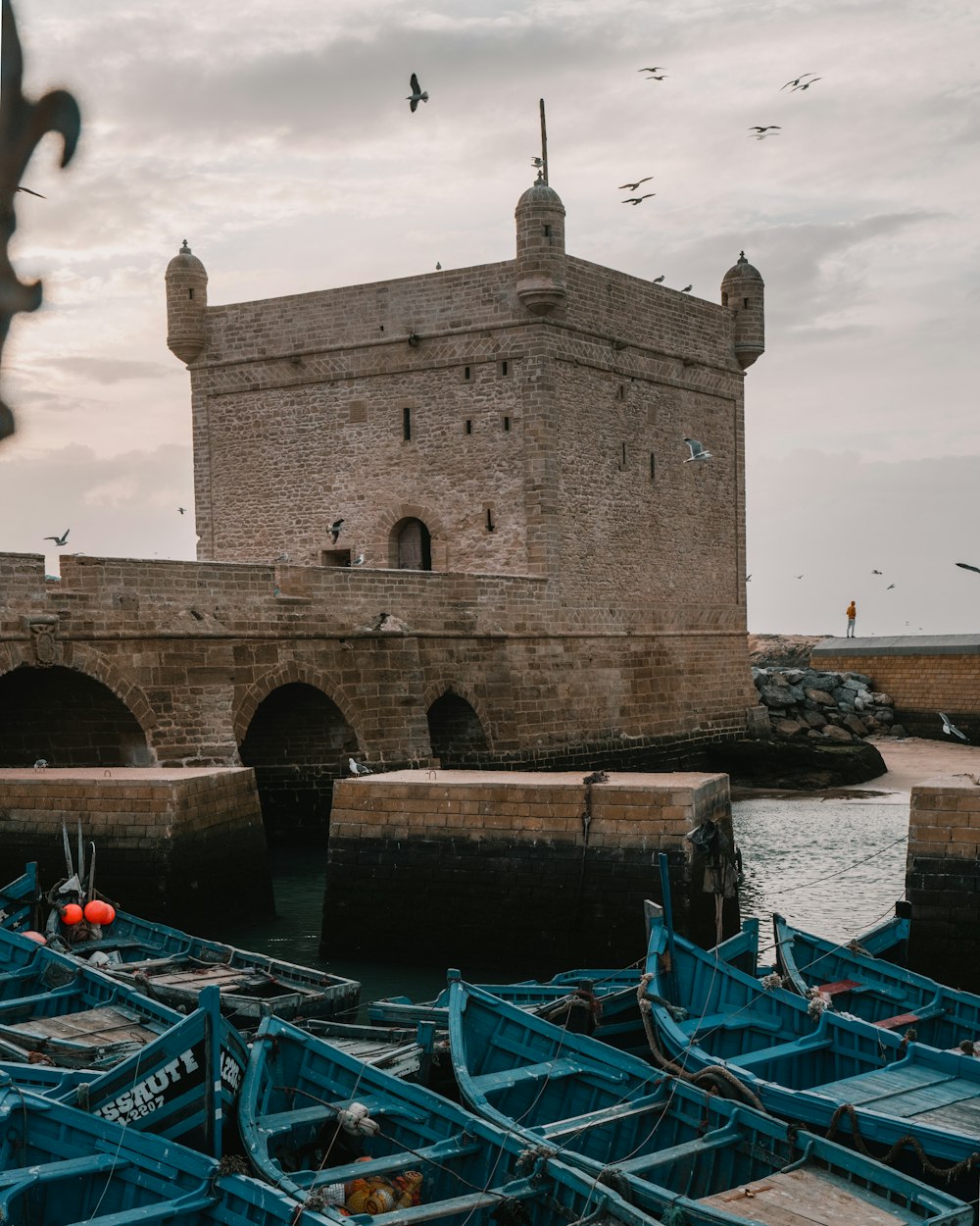 a group of blue boats sitting next to a stone building