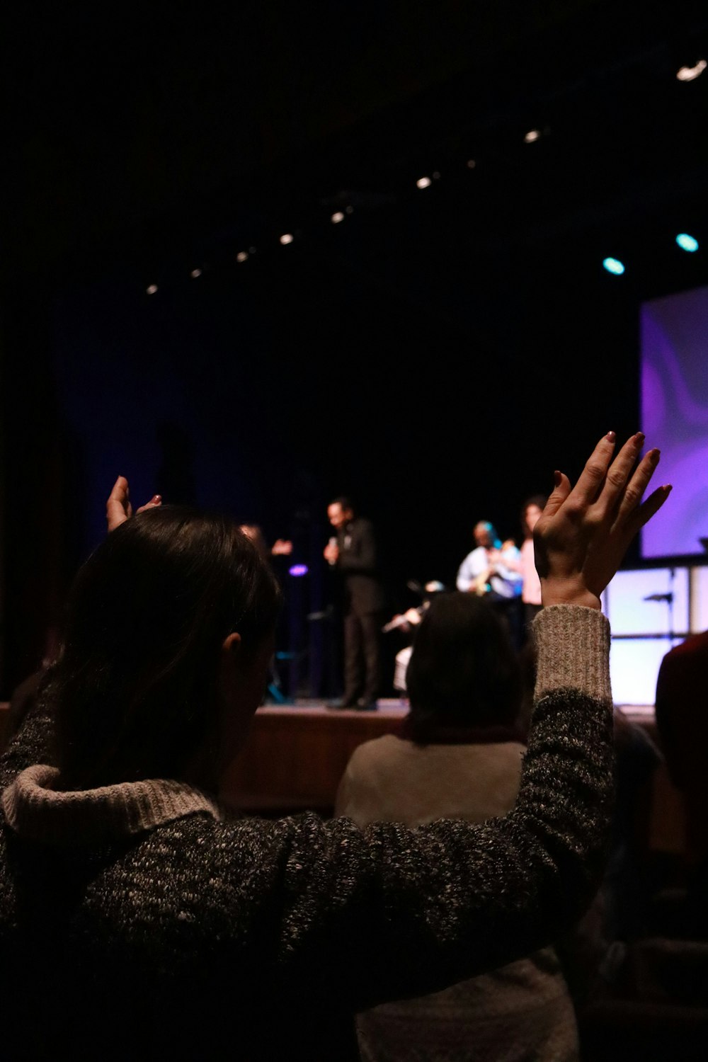 a group of people sitting in a room with their hands up