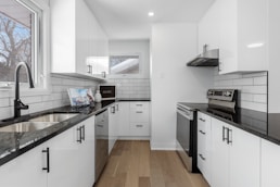 a kitchen with white cabinets and black counter tops