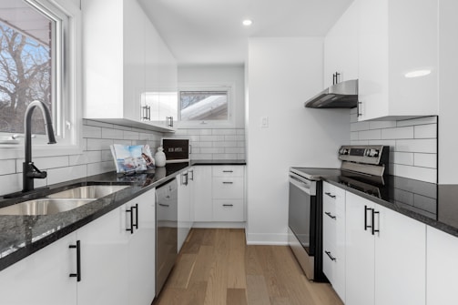 a kitchen with white cabinets and black counter tops