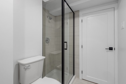 a white toilet sitting next to a walk in shower