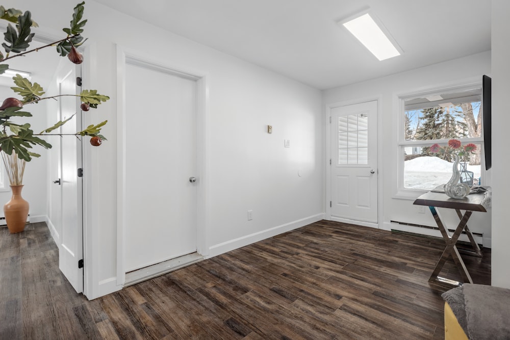 a white room with wood floors and a vase with flowers
