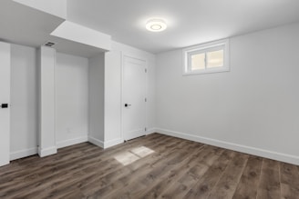 an empty room with white walls and wooden floors
