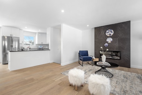 A modern living room showcasing a stylish modular kitchen with clean lines and navy blue accents.