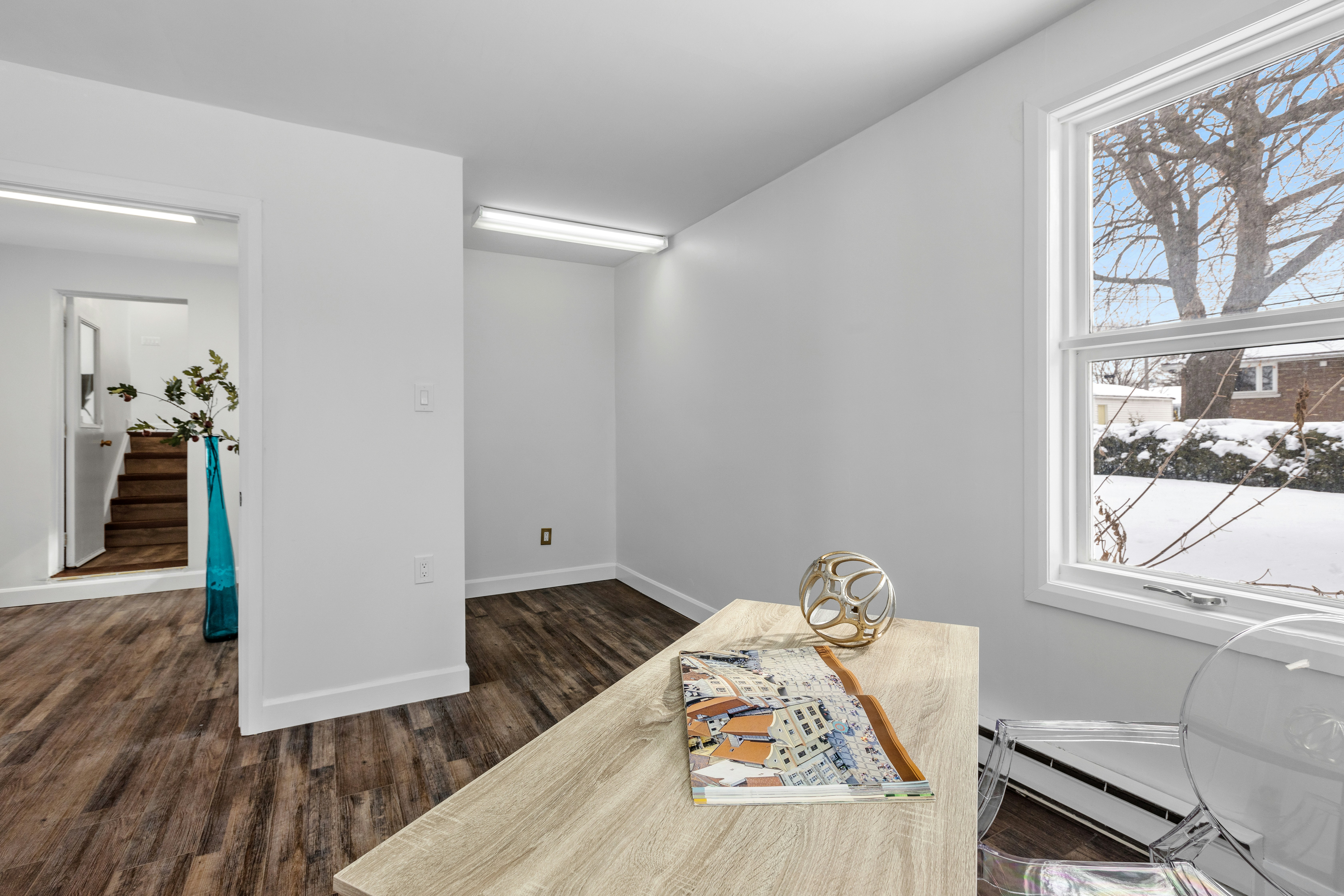 a white room with wood flooring and a large window