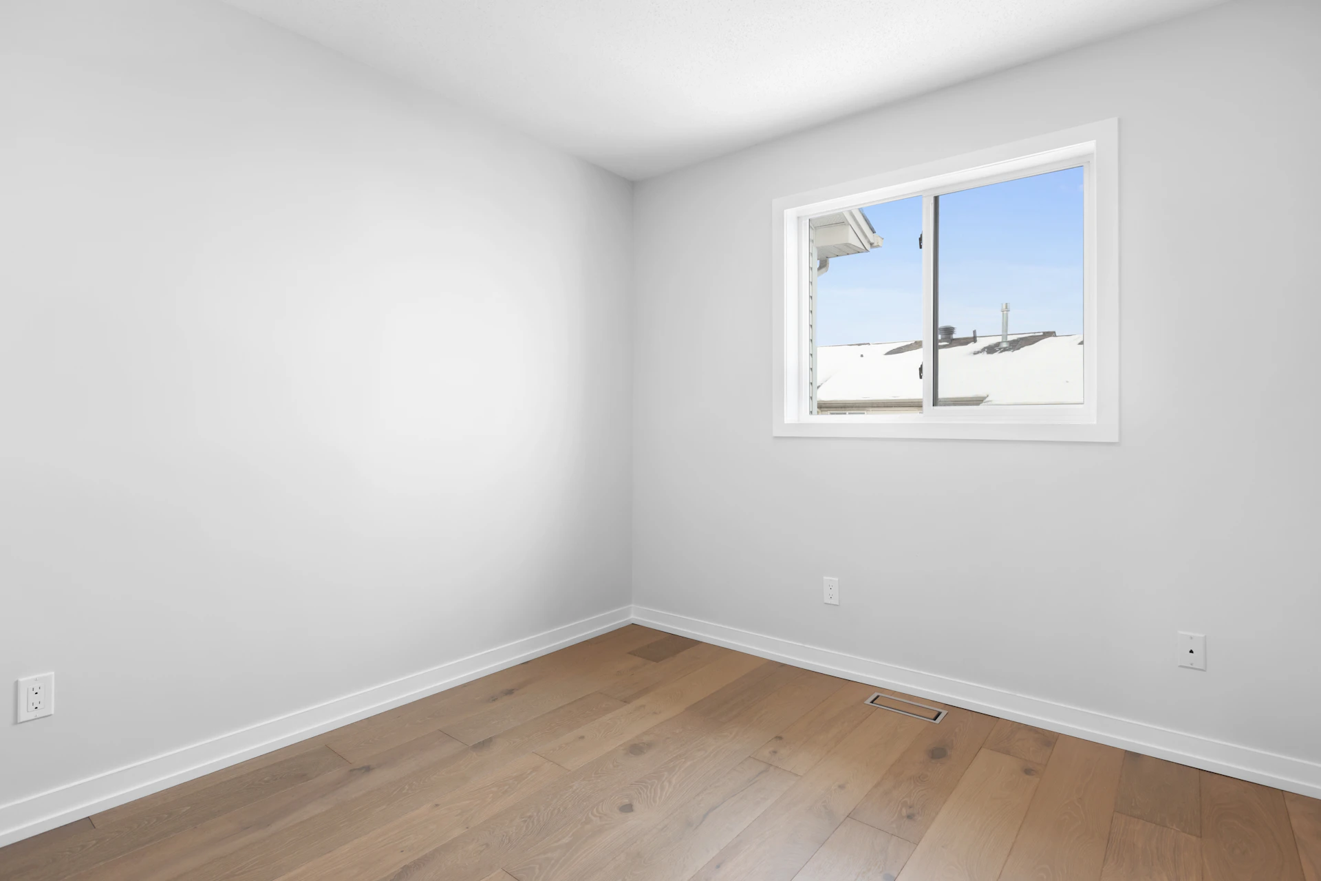 an empty room with a window and hard wood floor