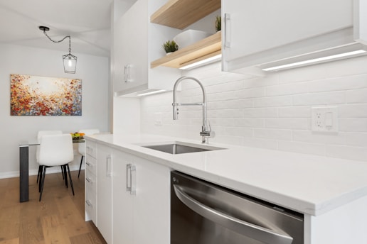 a kitchen with a sink, dishwasher and a painting on the wall
