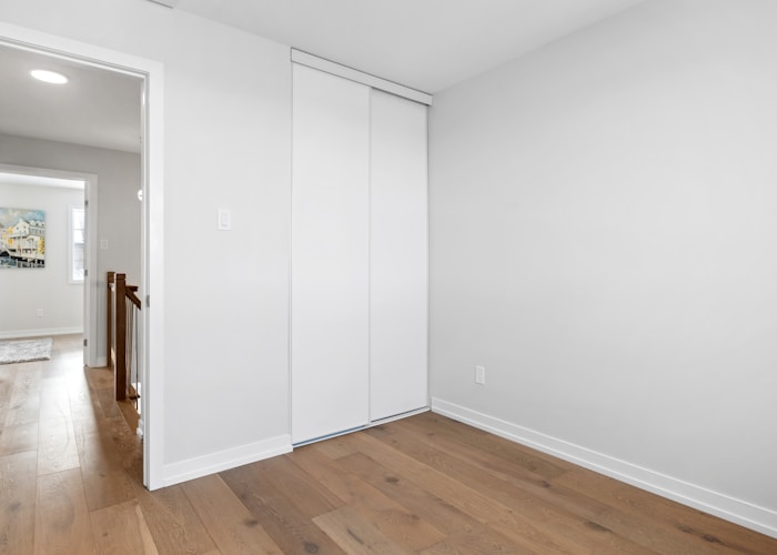 an empty room with white walls and wooden floors