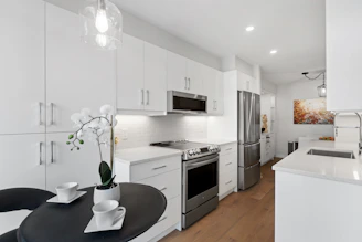 a kitchen with white cabinets and stainless steel appliances