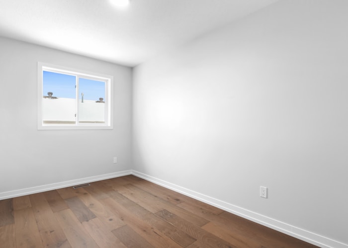 an empty room with a window and hard wood floor