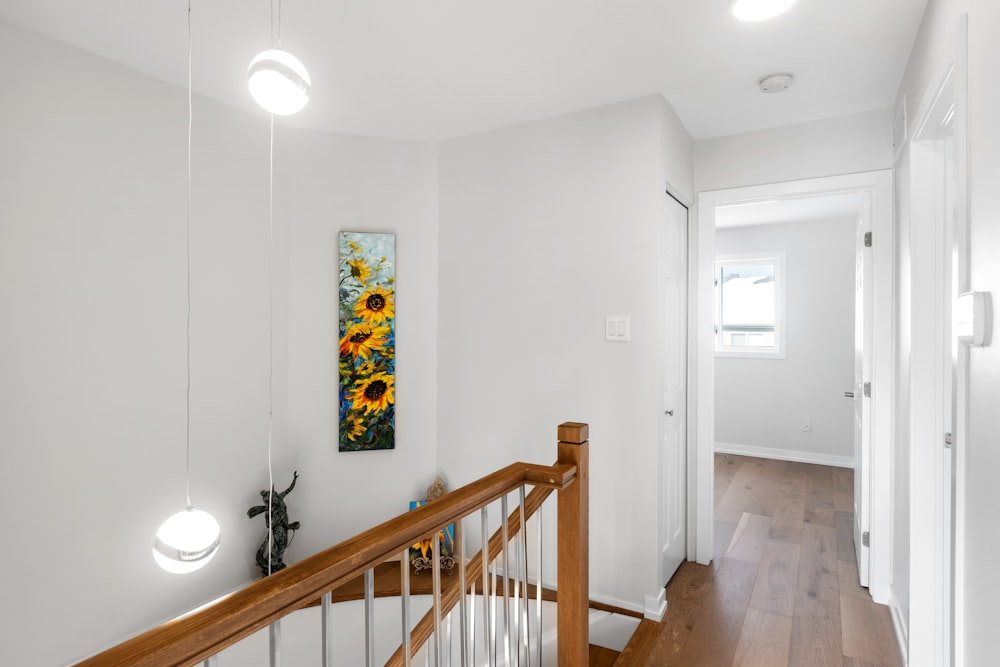 a hallway with a wooden banister and a painting on the wall