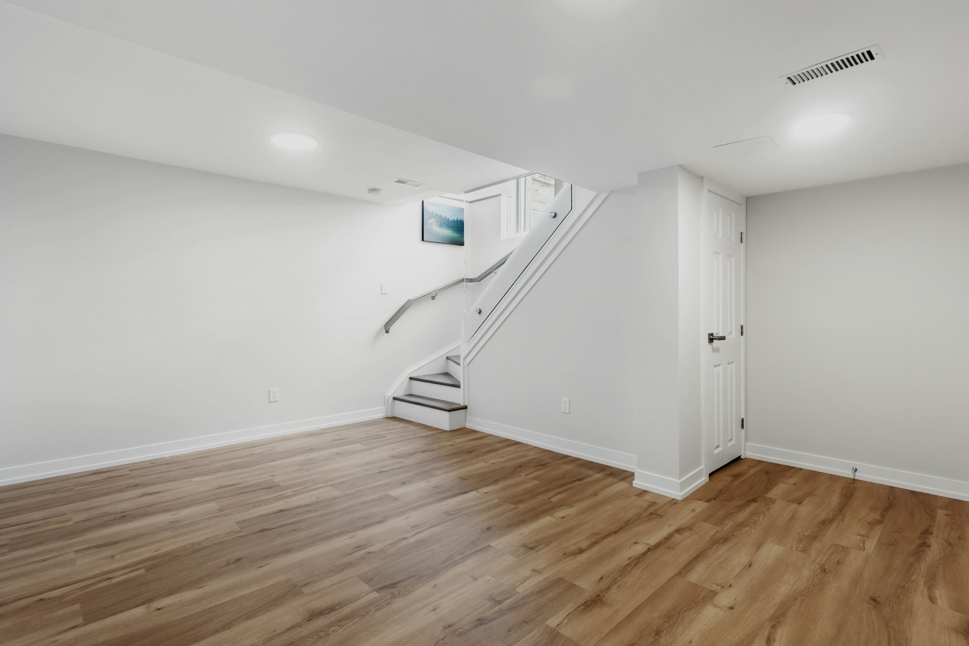 an empty room with a staircase and hard wood floors
