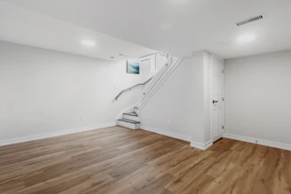 an empty room with a staircase and hard wood floors