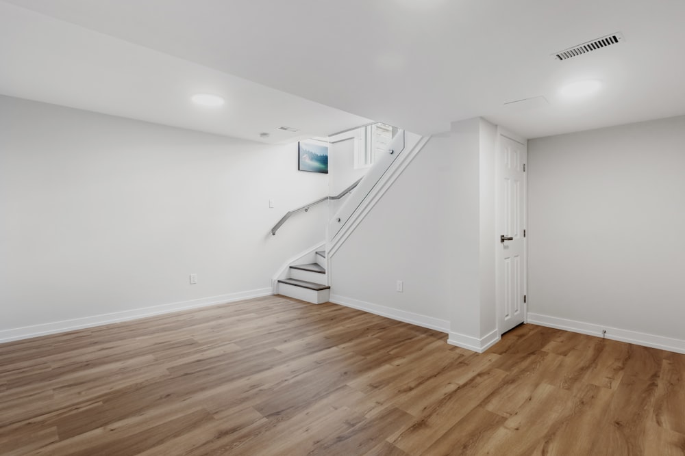 an empty room with a staircase and hard wood floors