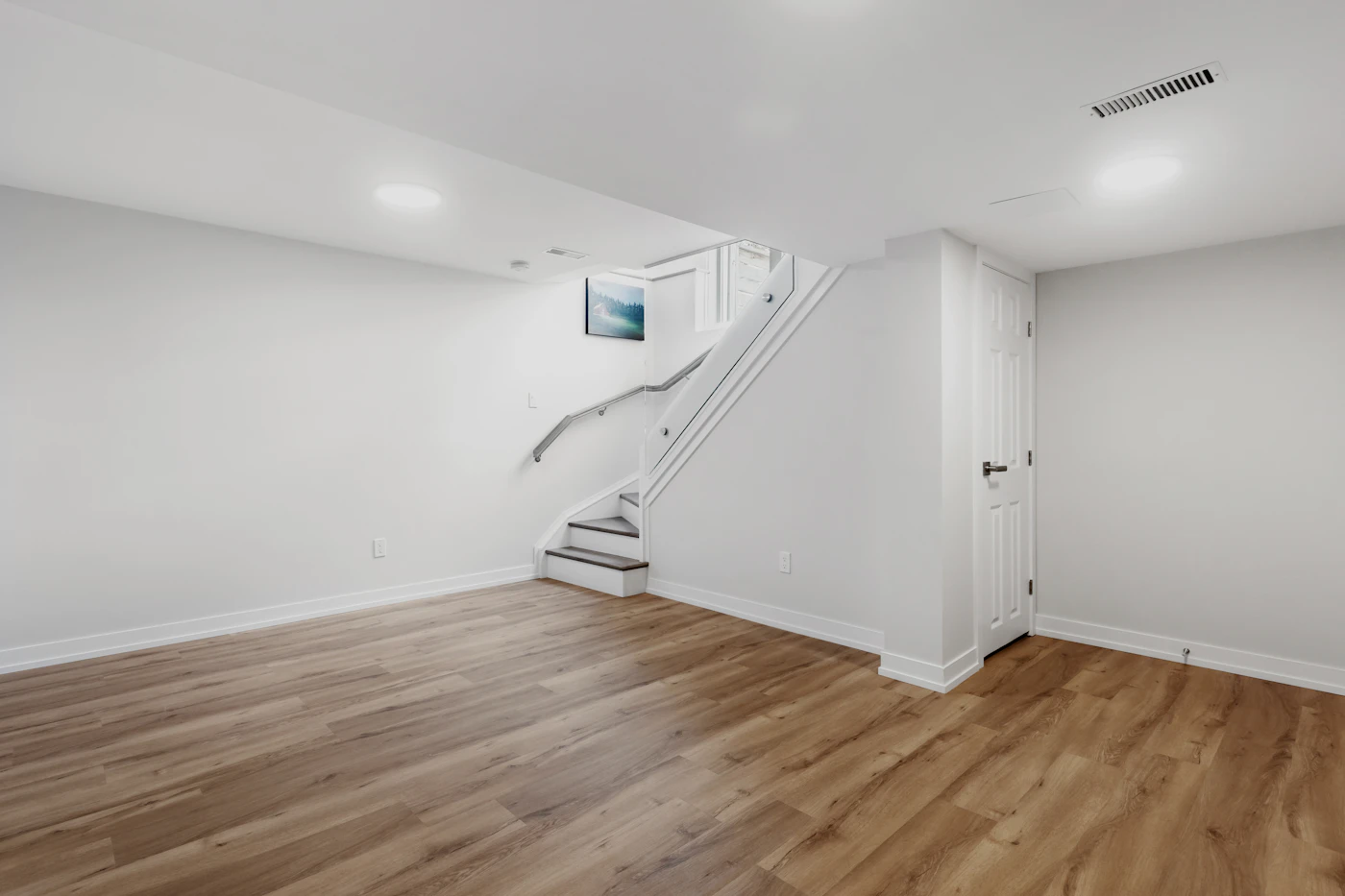 Renovated basement room with staircase and wood-look flooring