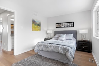 a bedroom with a bed, nightstands and a painting on the wall