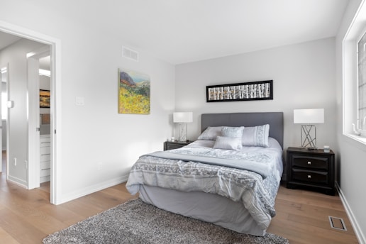 a bedroom with a bed, nightstands and a painting on the wall