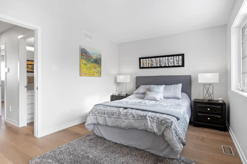 A bedroom transformed with a calming grey shade, showing the contrast between old and new paint.