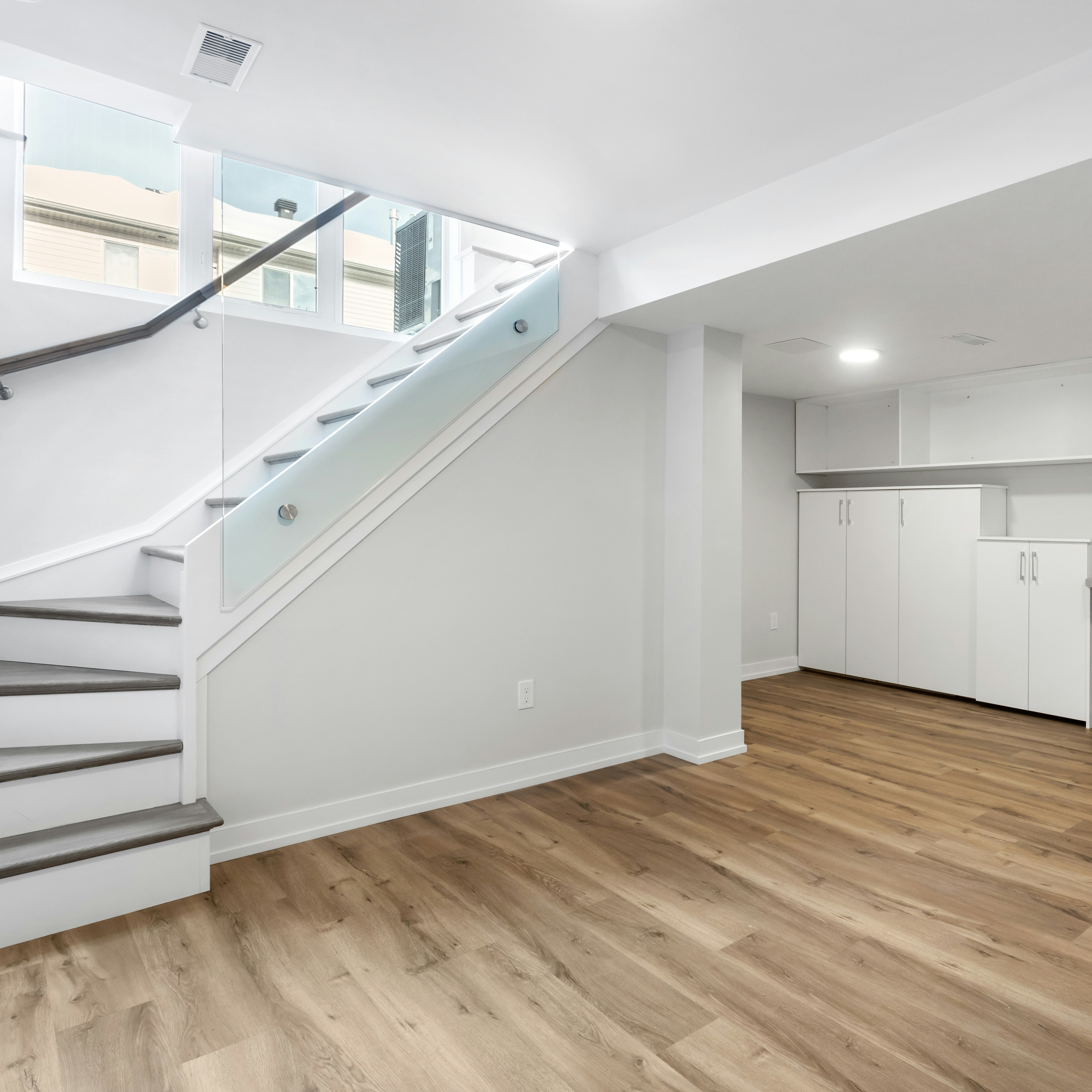 an empty room with a desk, computer, and stairs